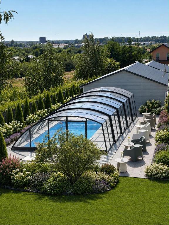 a garden with a glass building with a swimming pool at Pogodne Domki in Darłowo