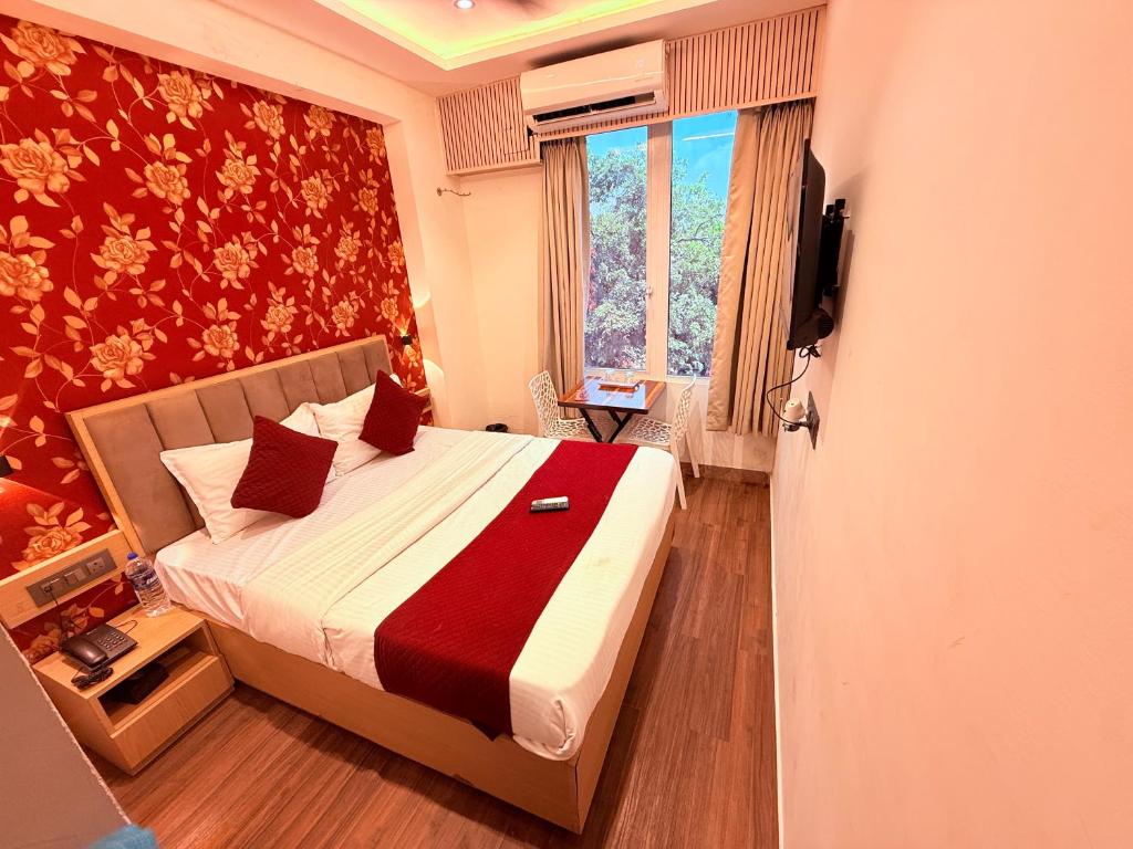 a bedroom with a bed and a window and a television at Hotel Iris Inn - Near Lodha Palava, Dombivali in Dombivli