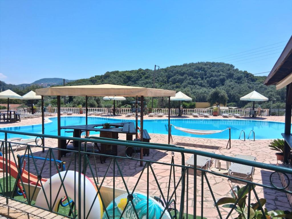 a large swimming pool with a table and a volley ball at Filoxenia Studios and Mermaid Pool in Paleokastritsa
