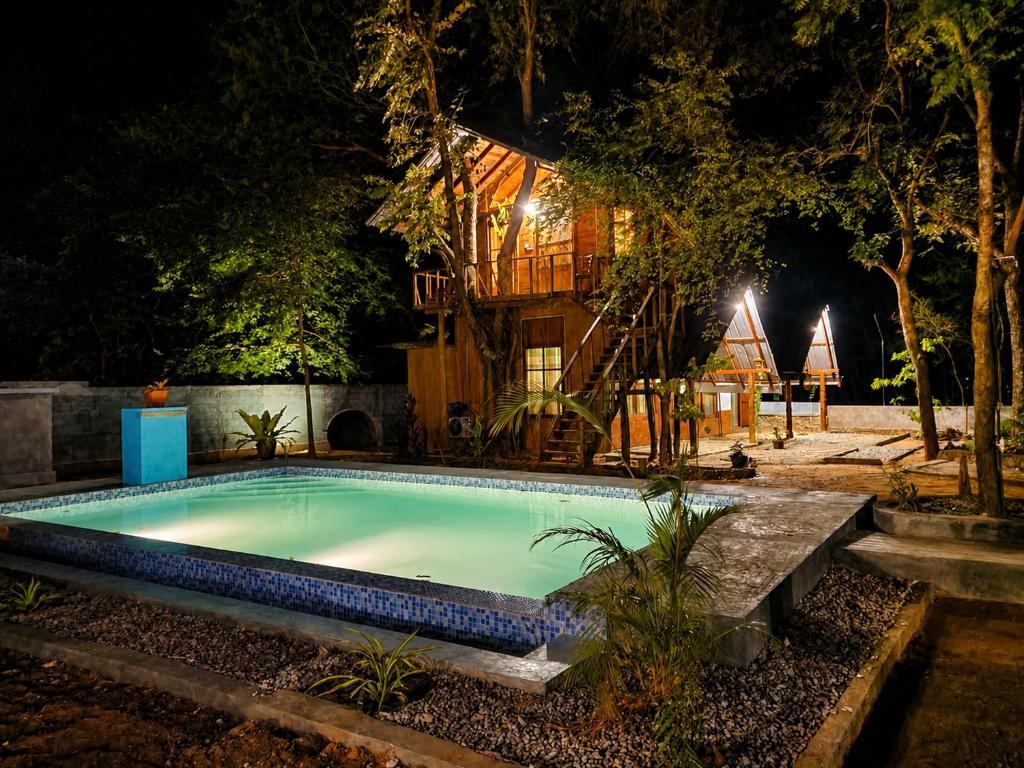 a swimming pool at night with a house in the background at wood cabin sigiriya in Sigiriya