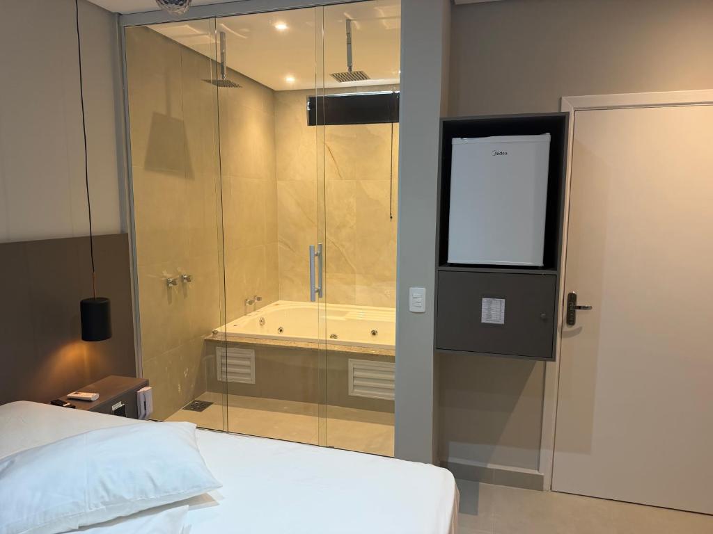 a bathroom with a bed and a shower with a tub at Wish Suítes in Campinas