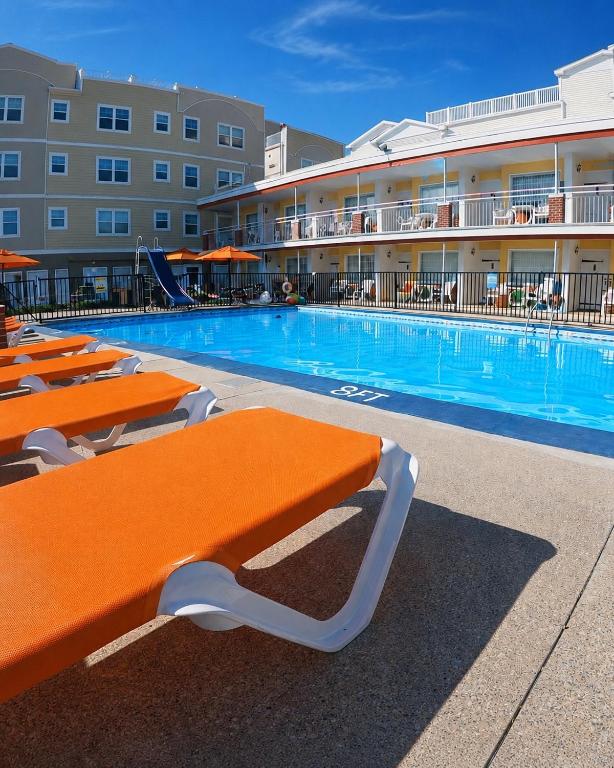 a large swimming pool with orange benches in front of a hotel at Sea Chest Motel in Wildwood Crest