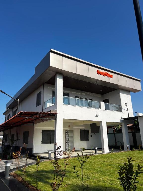 a white building with a red sign on it at Desai Villa - Pawna Lake in Wadgaon