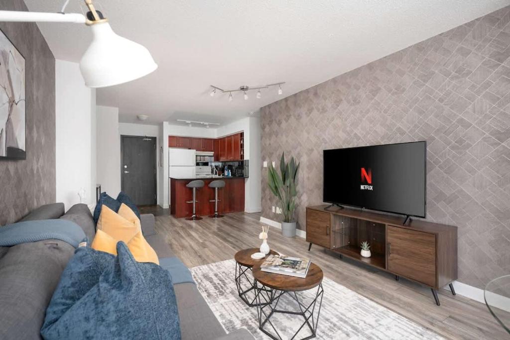 a living room with a couch and a flat screen tv at Modern King Suite Steps to Eaton Centre in Toronto