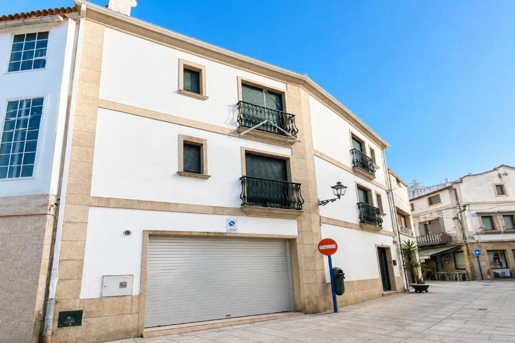 a white building with a garage door on a street at Casa Turística Mareira O Grove in O Grove