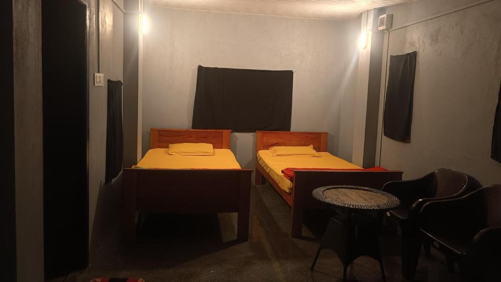 a small room with two beds and a chair at Rimaaia homestay in Lāitlyngkot