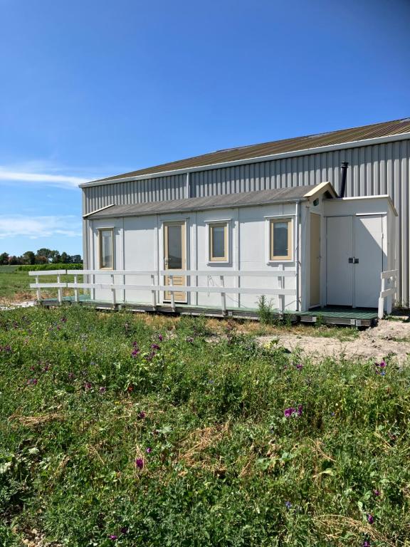 a white building with a garage on a field at Strandelijk plekje in Nieuwerkerk