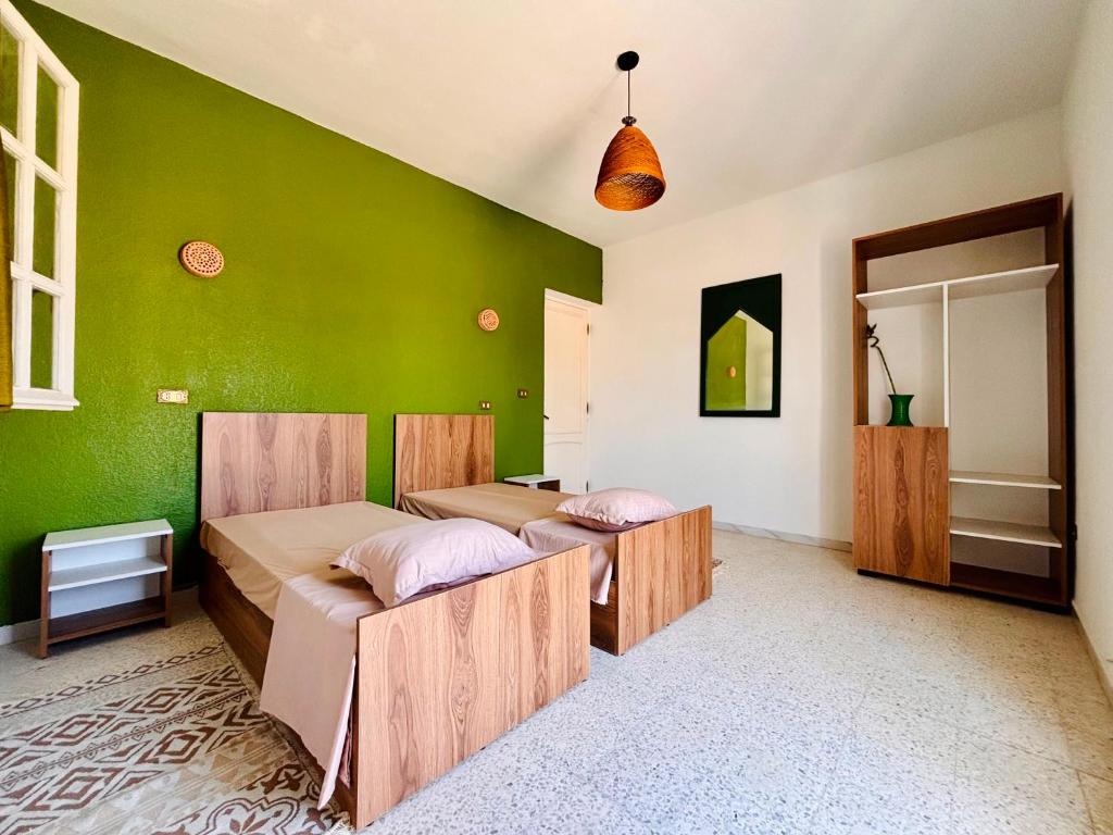 two beds in a room with green walls at Wostel Djerba Downtown in Houmt Souk