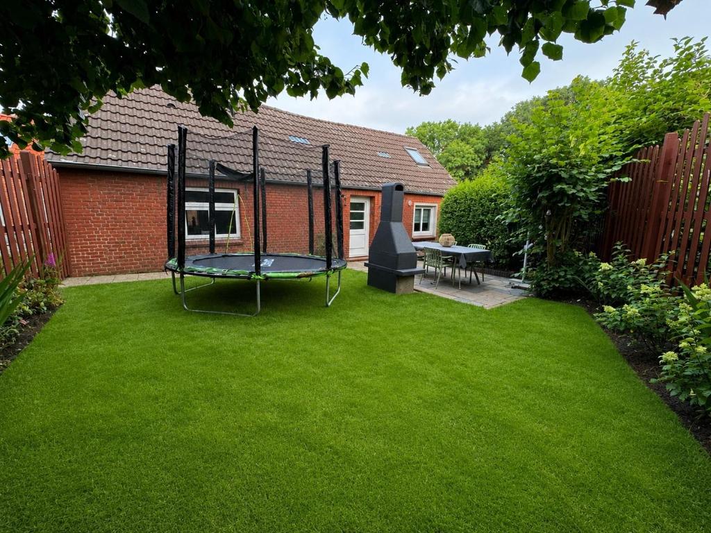 a small yard with a trampoline in the grass at Dat Lütte Huus - Ferienhaus nahe Greetsiel in Krummhörn