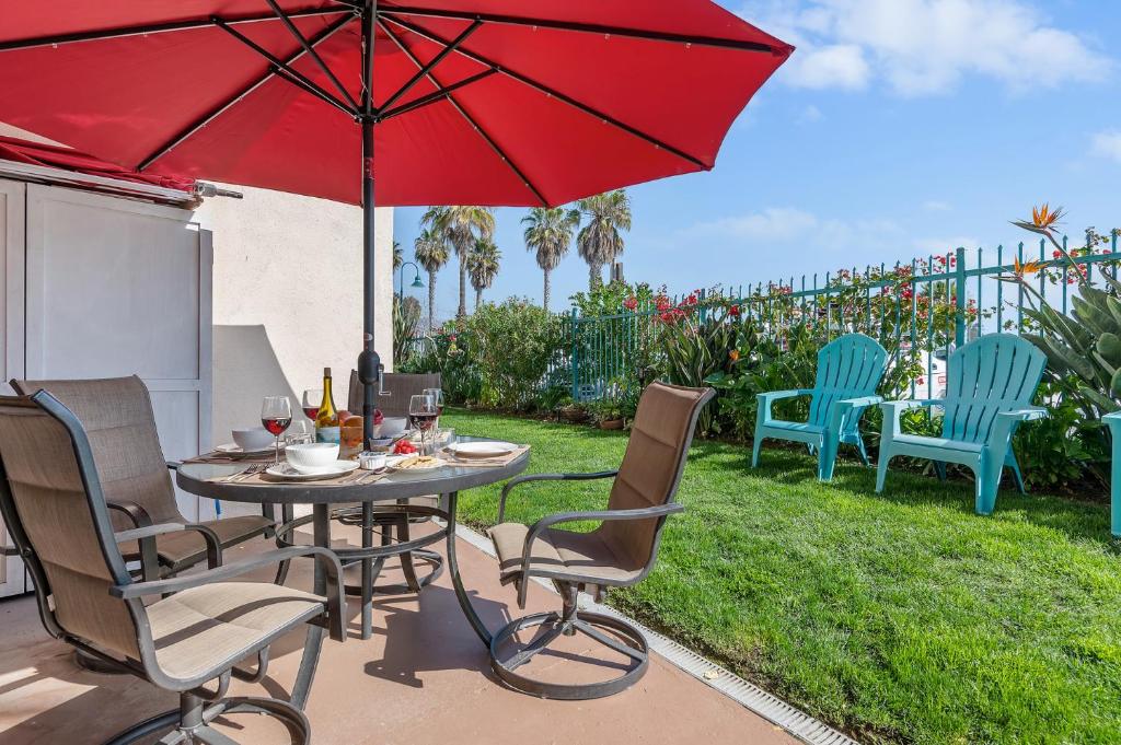 a patio with a table and chairs with a red umbrella at Carpinteria Shores CS 103 in Carpinteria