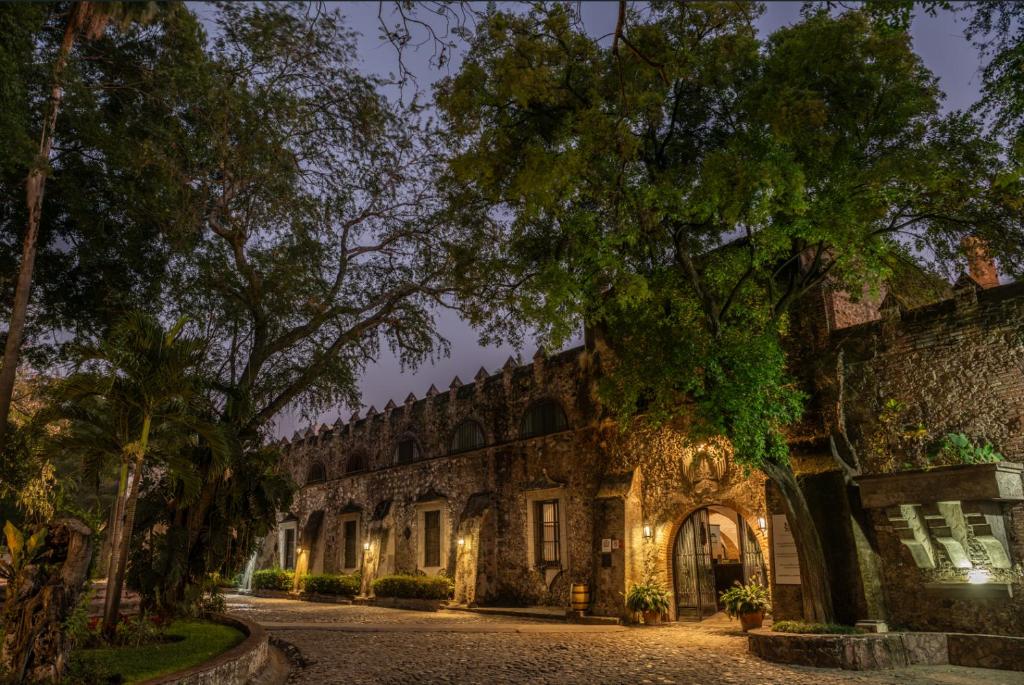 an old stone building with trees and lights at Hotel Hacienda Vista Hermosa in Tequesquitengo