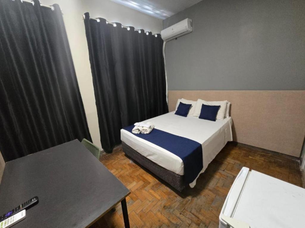 ein Schlafzimmer mit einem Bett mit schwarzen Vorhängen und einem Tisch in der Unterkunft Hotel Divinopolis Center - Alguel de Temporada in Divinópolis