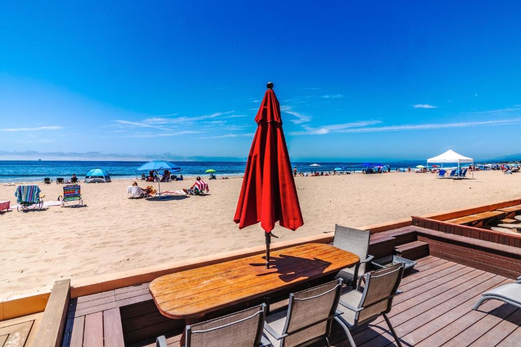 a wooden table with a red umbrella on the beach at Carpinteria Shores CS 110 in Carpinteria