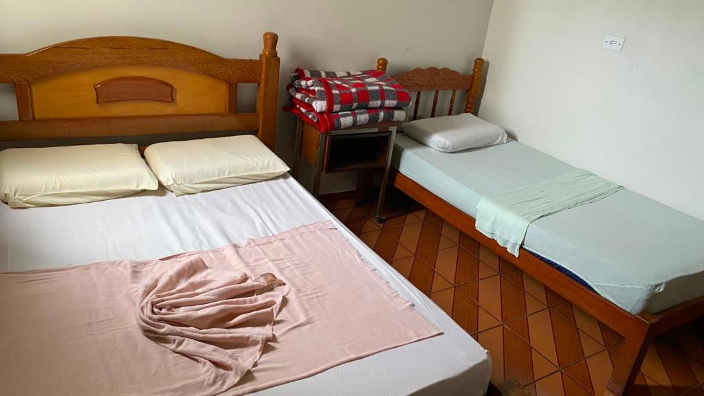 a room with two beds and a table with a bedskirts at Hotel Gênio in Pouso Alegre
