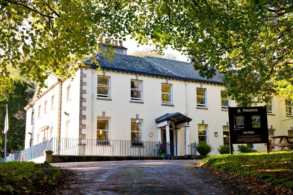 - un grand bâtiment blanc avec un panneau devant dans l'établissement YHA Penzance, à Penzance