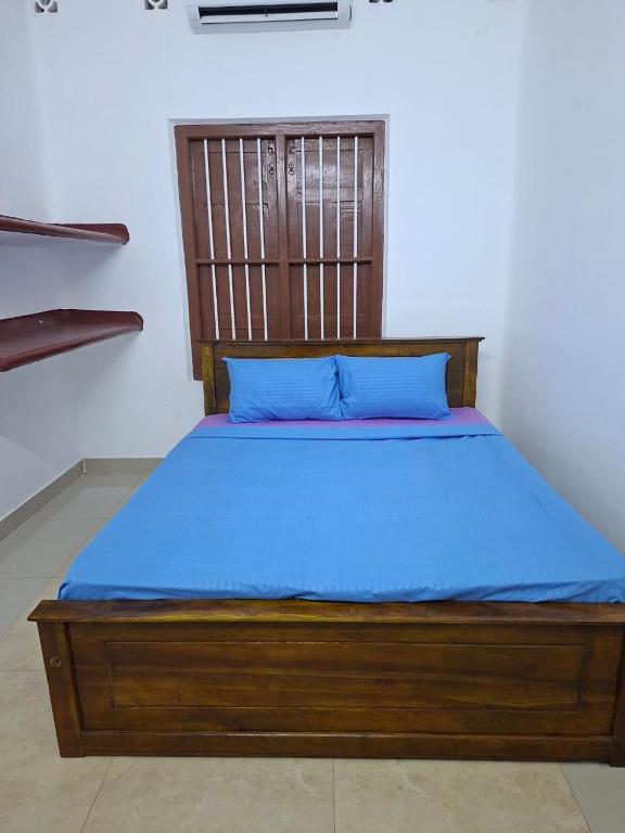 a wooden bed with blue sheets in a room at SN Villa in Jaffna