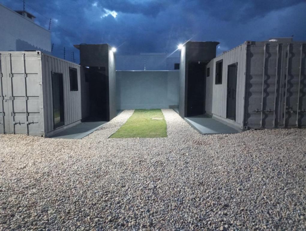 a building with two doors and a yard with gravel at Loft Conteiner in Primavera do Leste