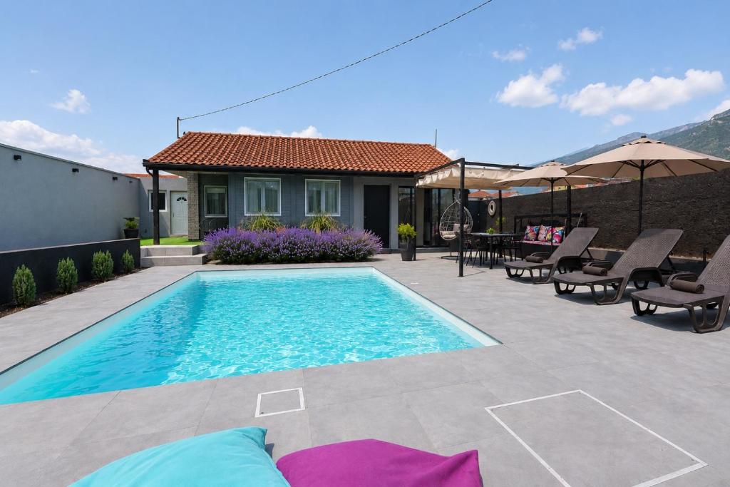 a swimming pool with chairs and a house at Villa Pantheon Mostar in Blagaj