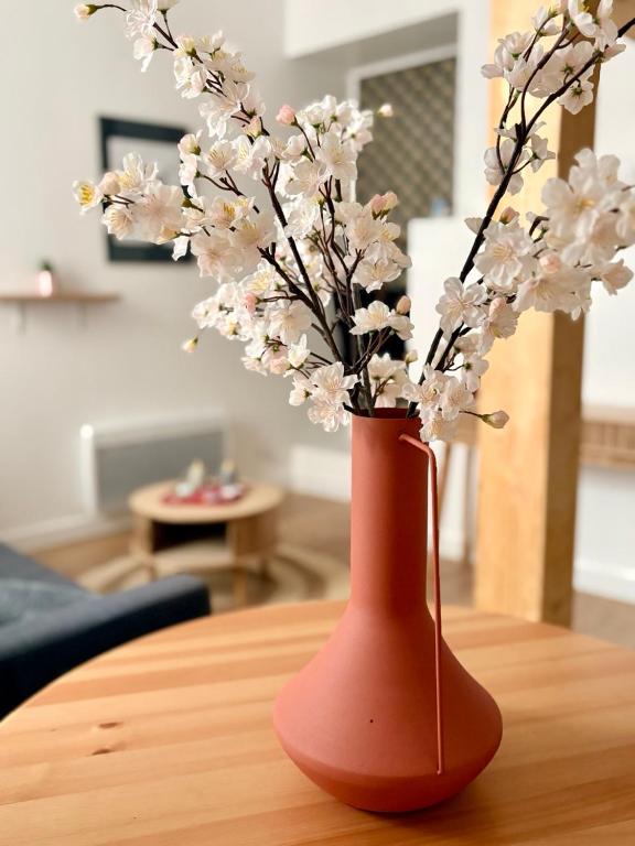 a red vase with flowers in it on a table at Le Notre Dame - Hyper centre in Angoulême