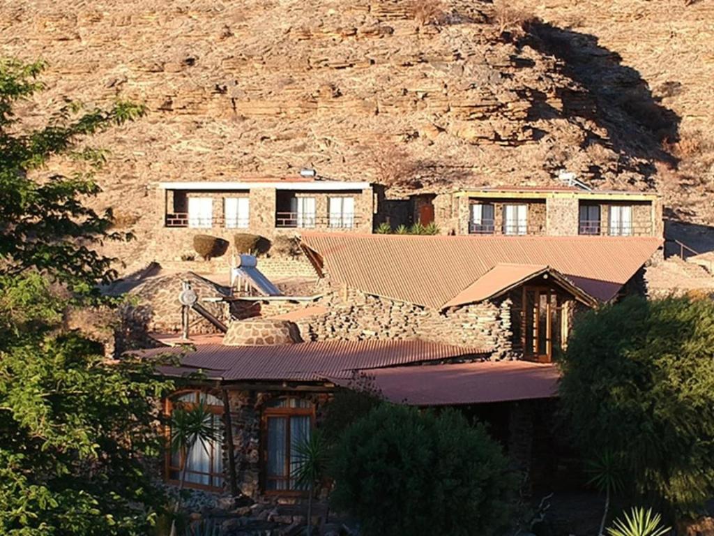 a house in front of a mountain at Zebra River Lodge in Maltahöhe