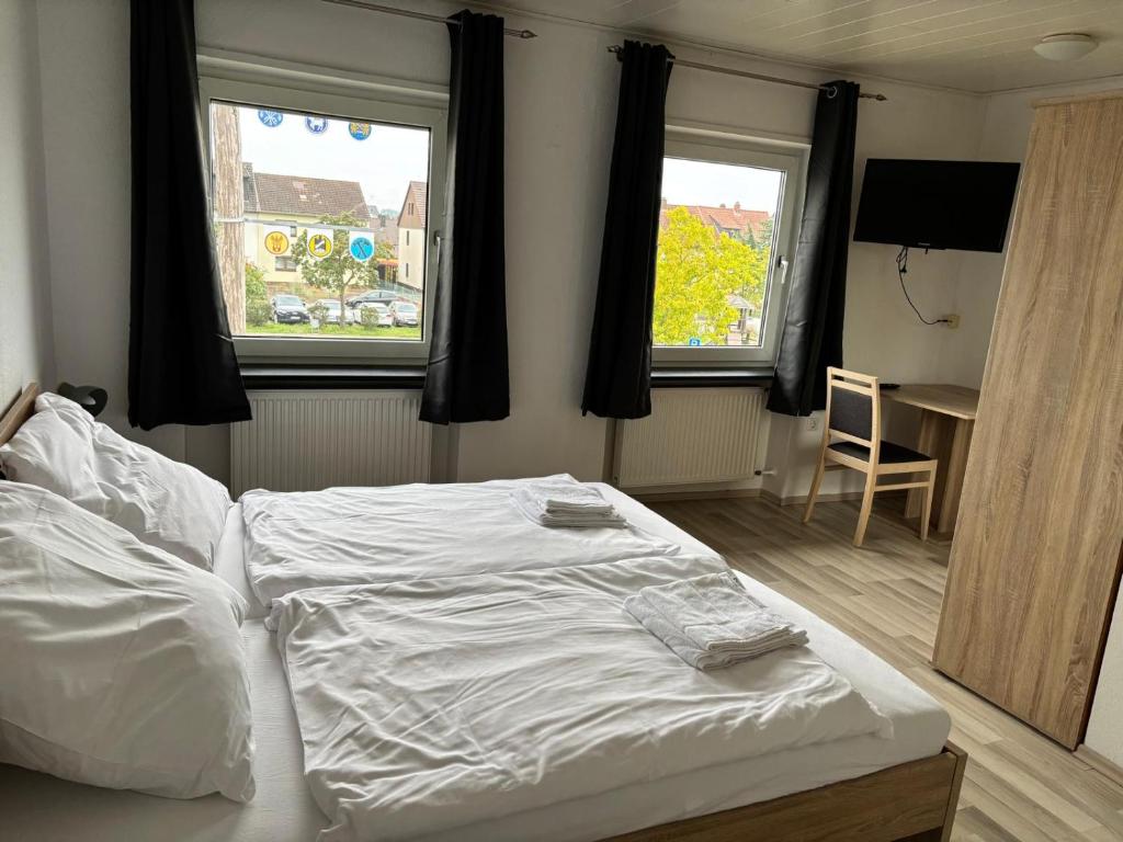a bedroom with a white bed and two windows at Pension DaVinci in Schwetzingen