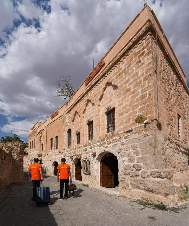 two men in orange vests standing in front of a building at Mons Masius Hotel Teras in Midyat