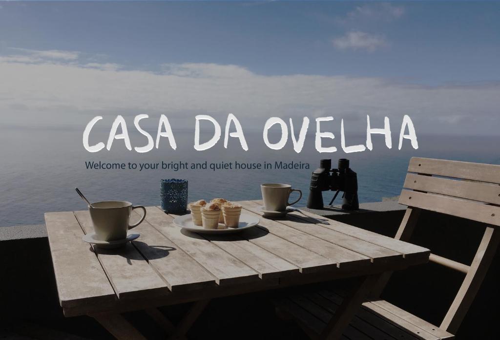 ein Holztisch mit zwei Tassen und Keksen darauf in der Unterkunft Casa da Ovelha I Madeira in Fajã da Ovelha