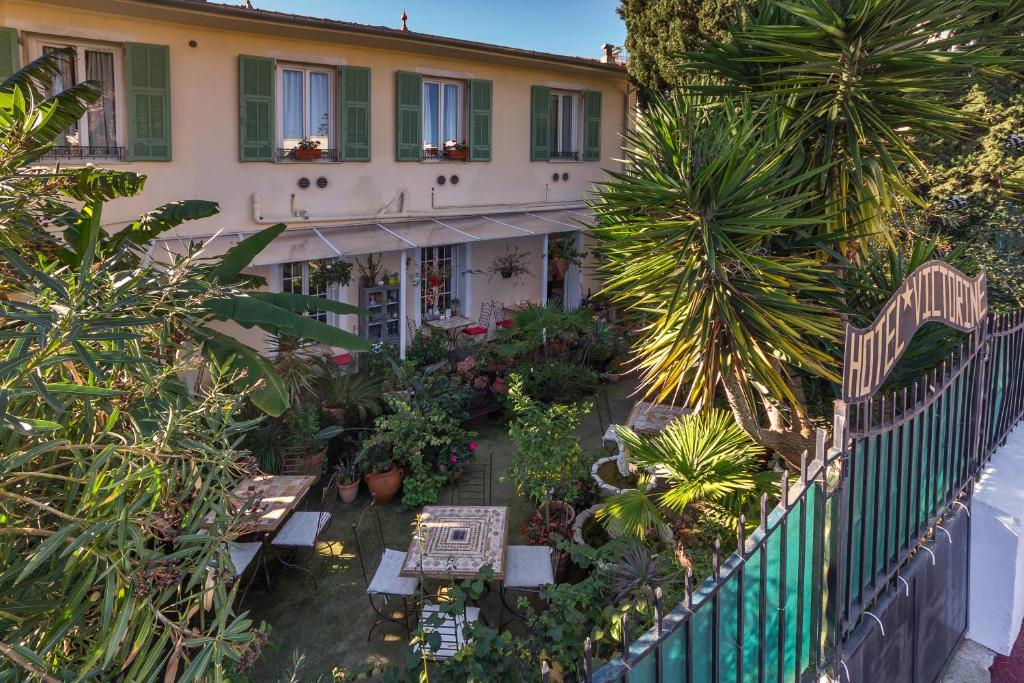 uma vista aérea de um edifício com plantas e mesas em Logis Hôtel Villa Victorine em Nice