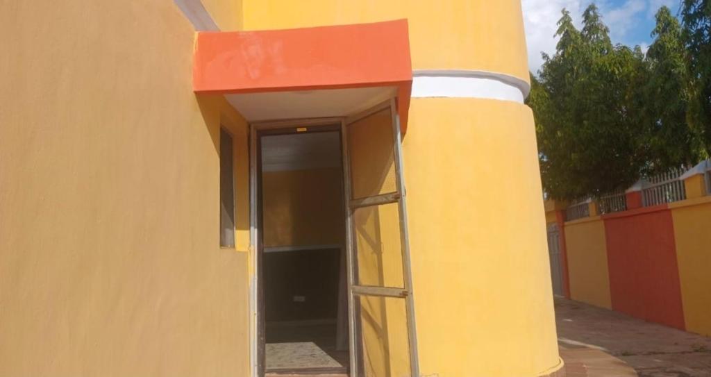a yellow building with a red roof and a doorway at Monarch Appartement in Oshogbo