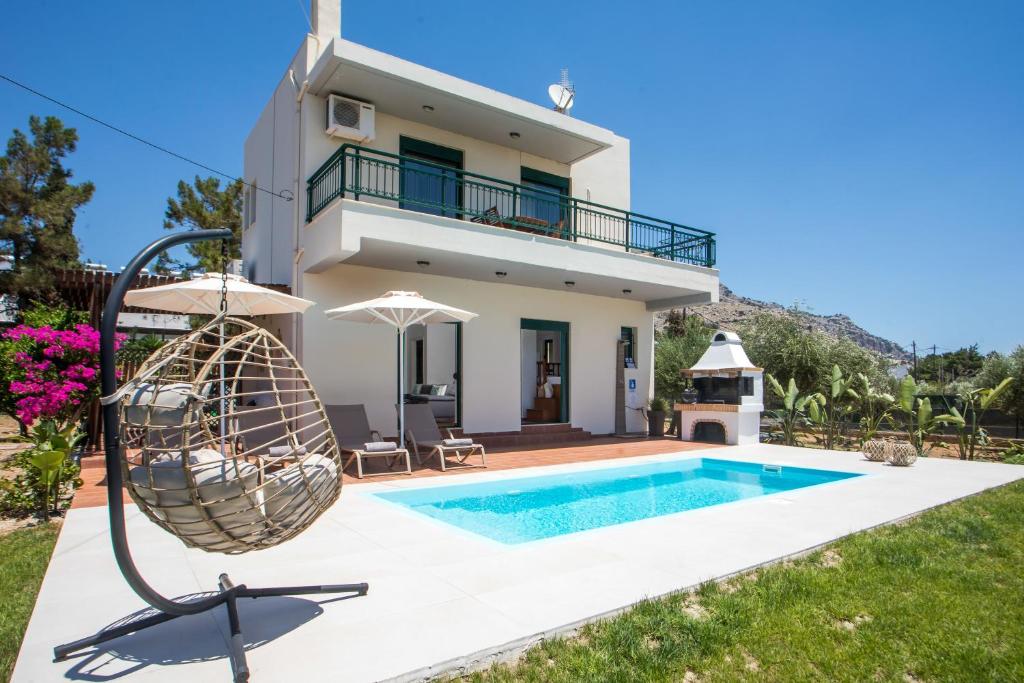 a villa with a swimming pool and a house at Villa Calliope Lardos in Lartos