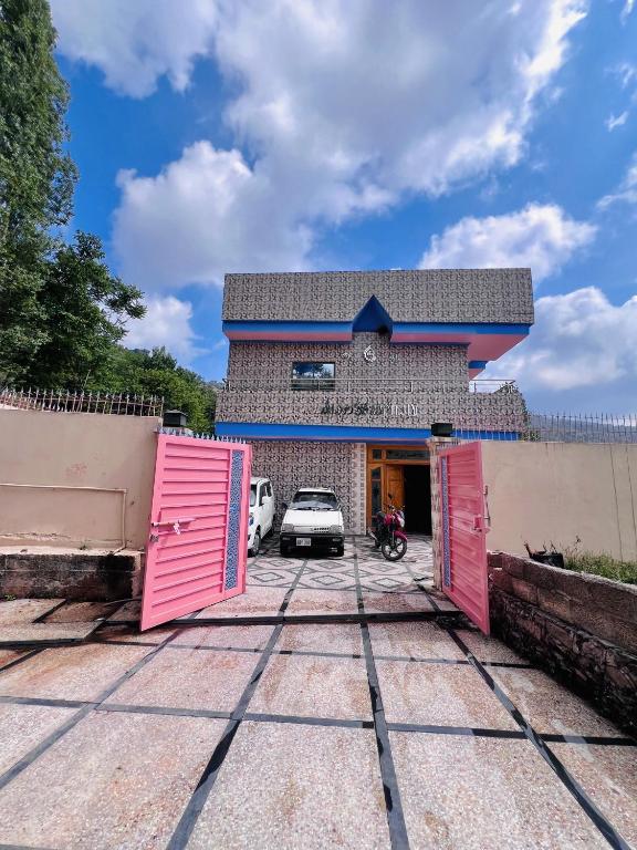 a building with pink doors and a car parked at umer cottage in Murree