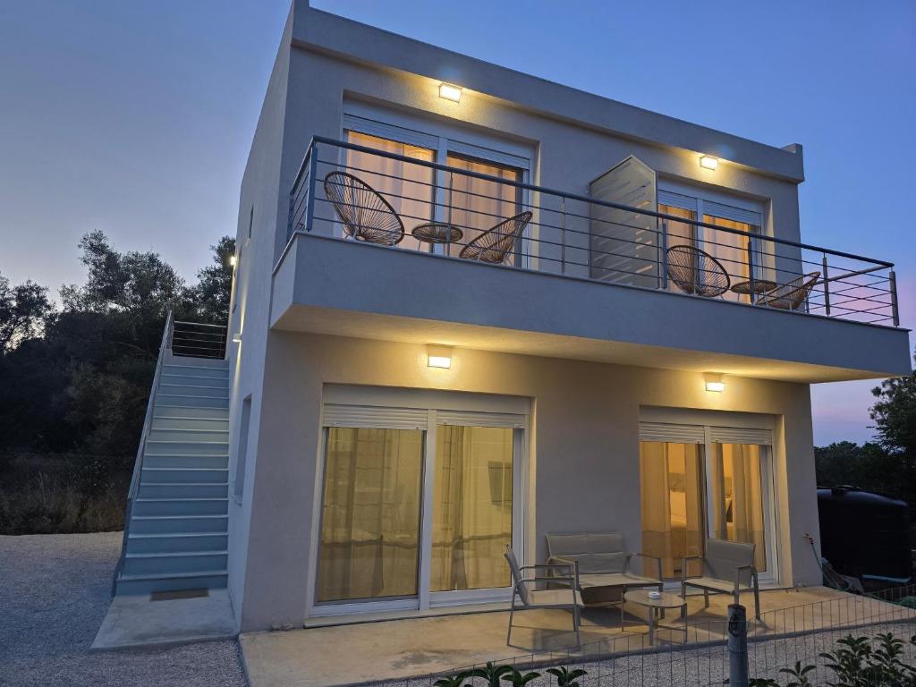 a white house with a staircase and a balcony at BLV Apartments in Tsoukalades