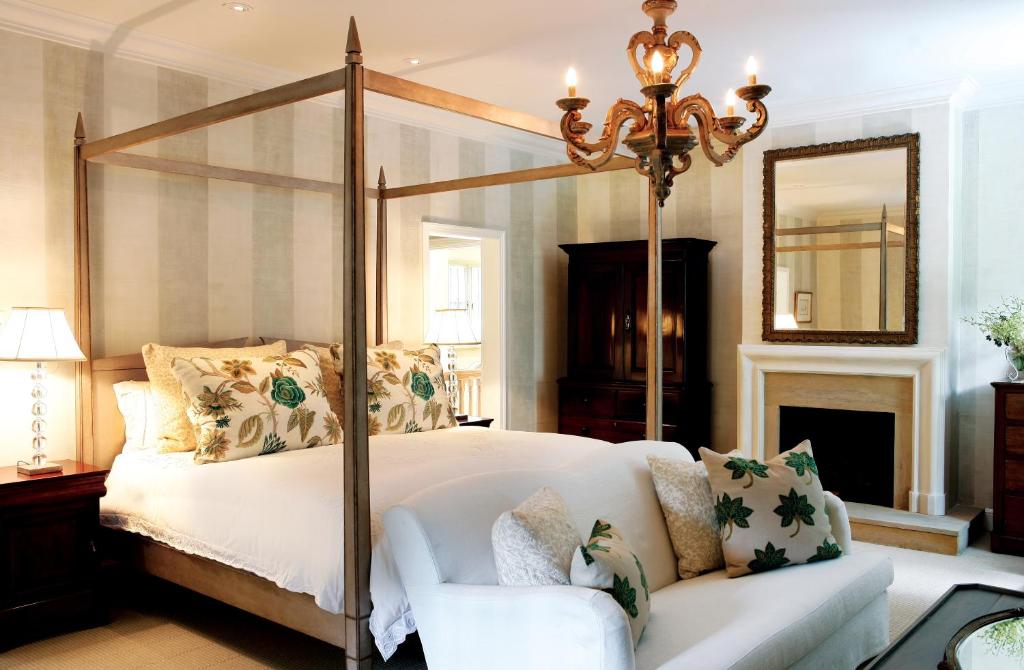 een slaapkamer met een hemelbed en een witte bank bij Hoeveld House in Johannesburg