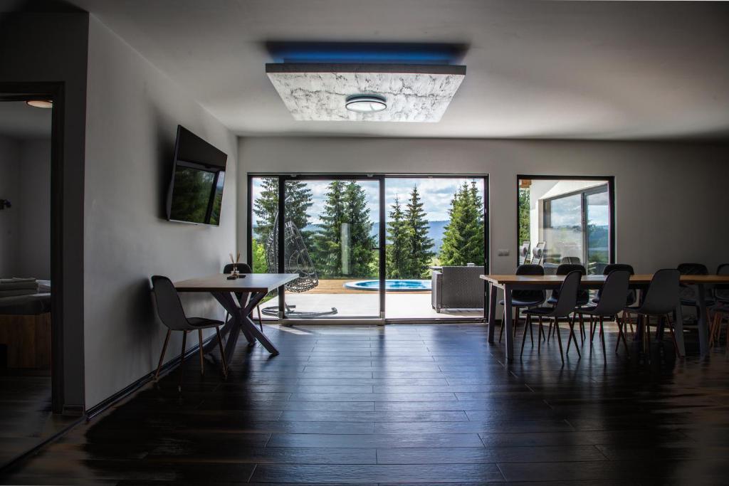 a dining room with tables and chairs and a large glass door at Cabana The One in Beliş