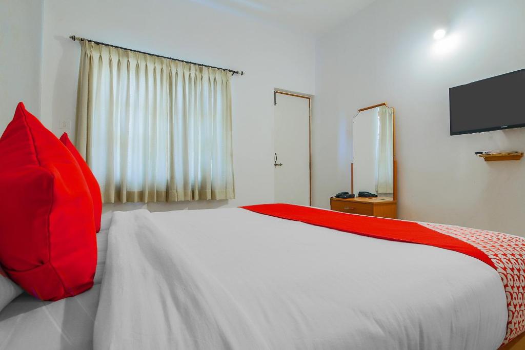 a bedroom with a large bed with a red pillow at Hotel O The Goan Courtyard in Goa