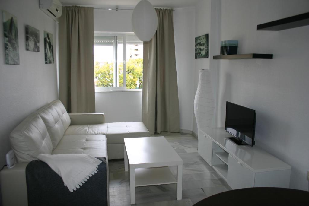 sala de estar blanca con sofá blanco y TV en Apartamento Las Adelfas, en Jerez de la Frontera