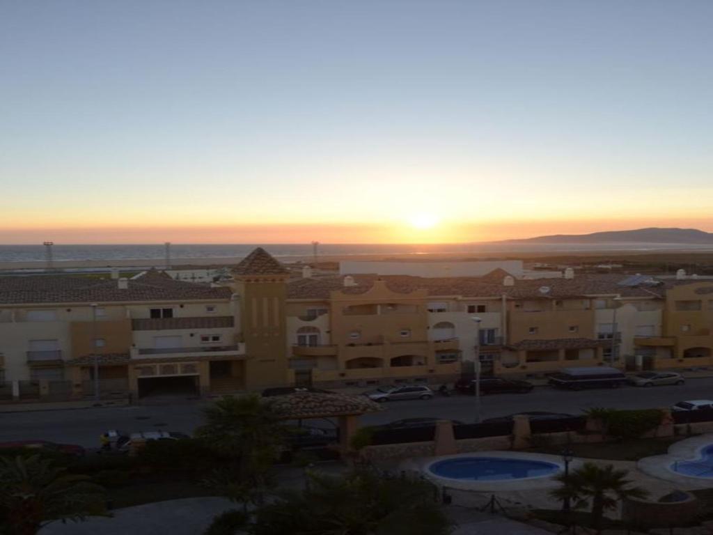 ein Sonnenuntergang über einer Stadt mit Gebäuden und einem Parkplatz in der Unterkunft Livingtarifa Apartamento Anhelo in Tarifa