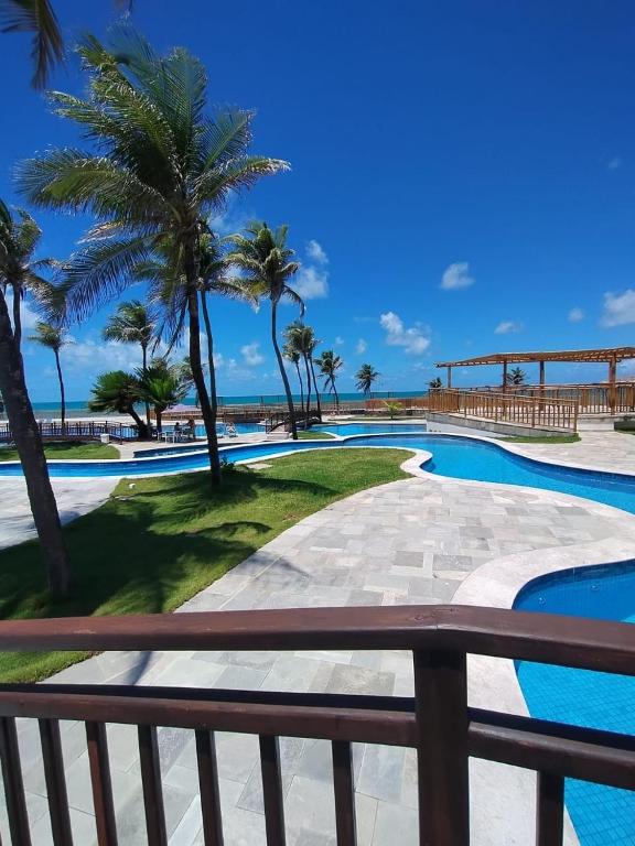 a view of a swimming pool with palm trees and the ocean at Pirâmide Palace Hotel in Natal