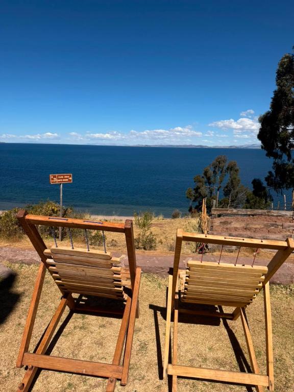 two wooden chairs sitting next to each other on the beach at Casa de Ruben - Lac Titicaca in Llachon