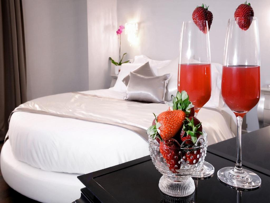 a bed with two wine glasses and strawberries on a table at Piazza di Spagna Suite de Charme in Rome