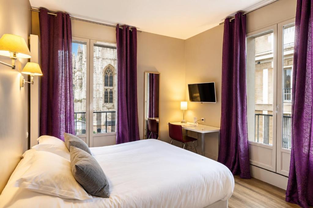 a bedroom with purple curtains and a bed with a desk at Hôtel Cardinal in Rouen
