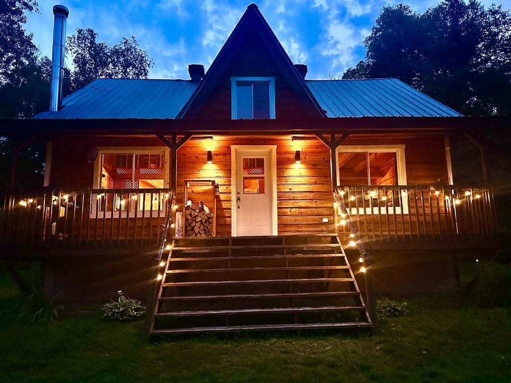 a wooden house with lights on the stairs at Repère de la Rivière - Bord de l'eau- Activités nautiques in Saint-Alexis-des-Monts