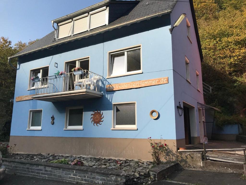 a blue building with people on a balcony at Veldenzer Hammer in Veldenz
