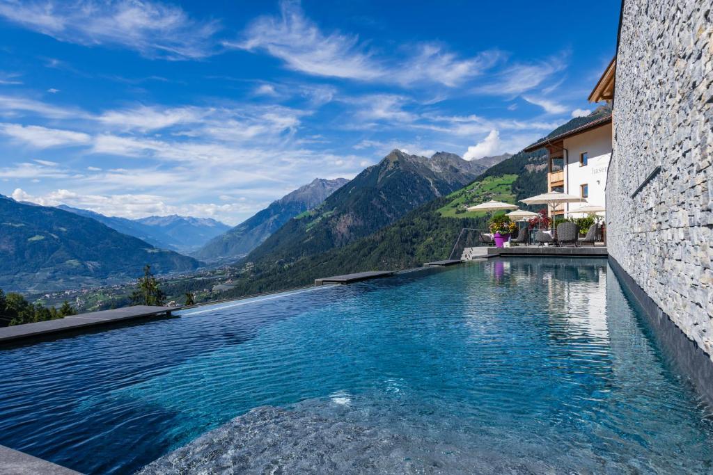 a hotel swimming pool with mountains in the background at Mountain Village Hasenegg in Schenna