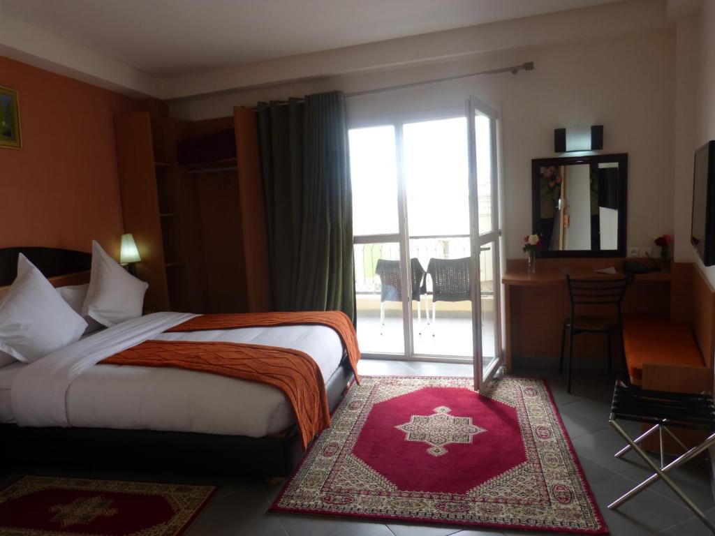 a hotel room with a bed and a large window at Hotel Arena Fes in Fès