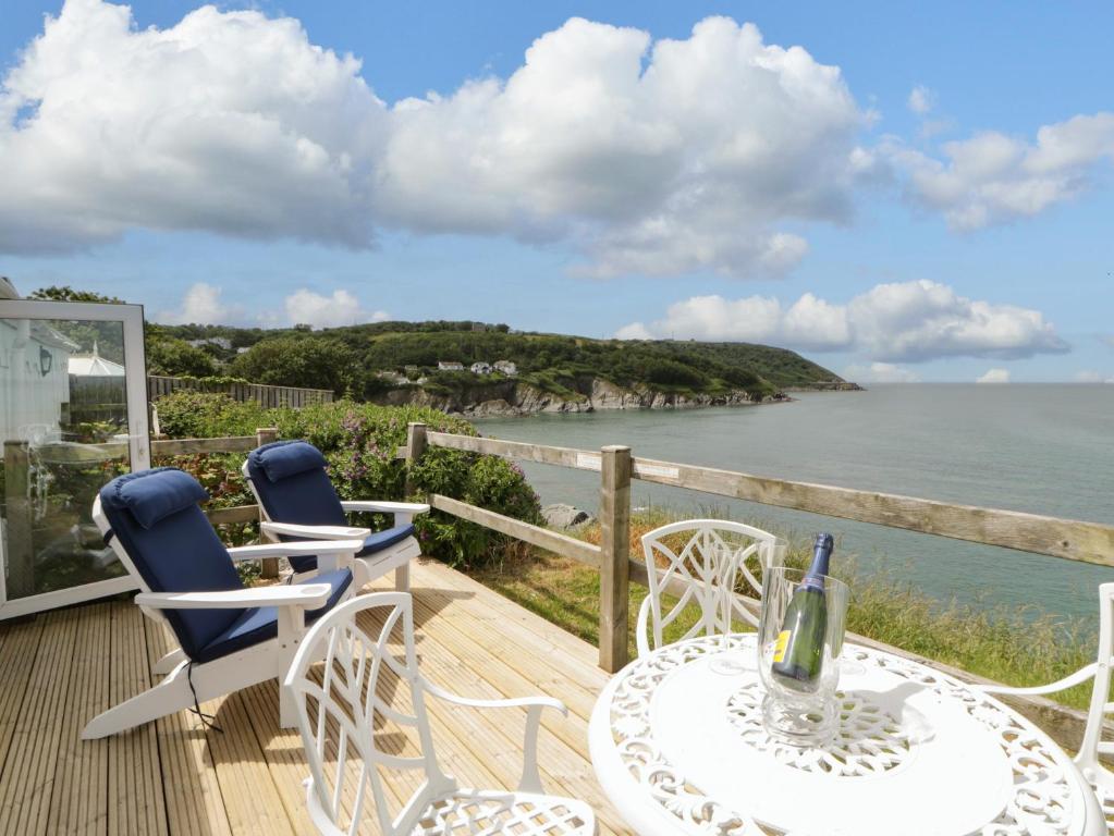 a deck with a table and chairs and the ocean at Clifftop Carriage in Aberporth