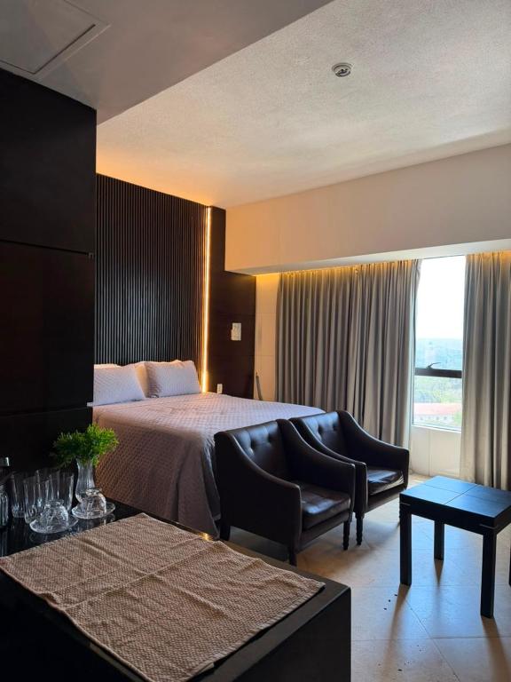 a hotel room with a bed and a couch and chairs at Tropical Executive Confort in Manaus