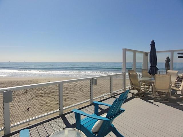 a deck with chairs and an umbrella on the beach at Padaro Sands in Carpinteria