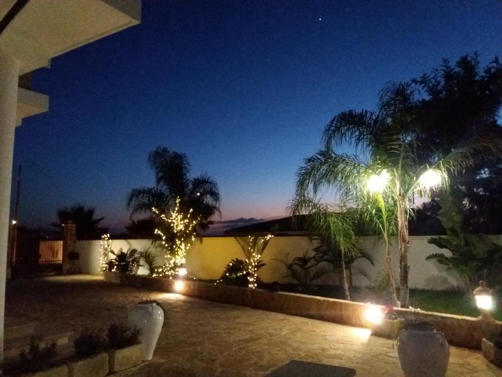 un patio notturno con palme e luci di B&B Cesaranum a Casarano