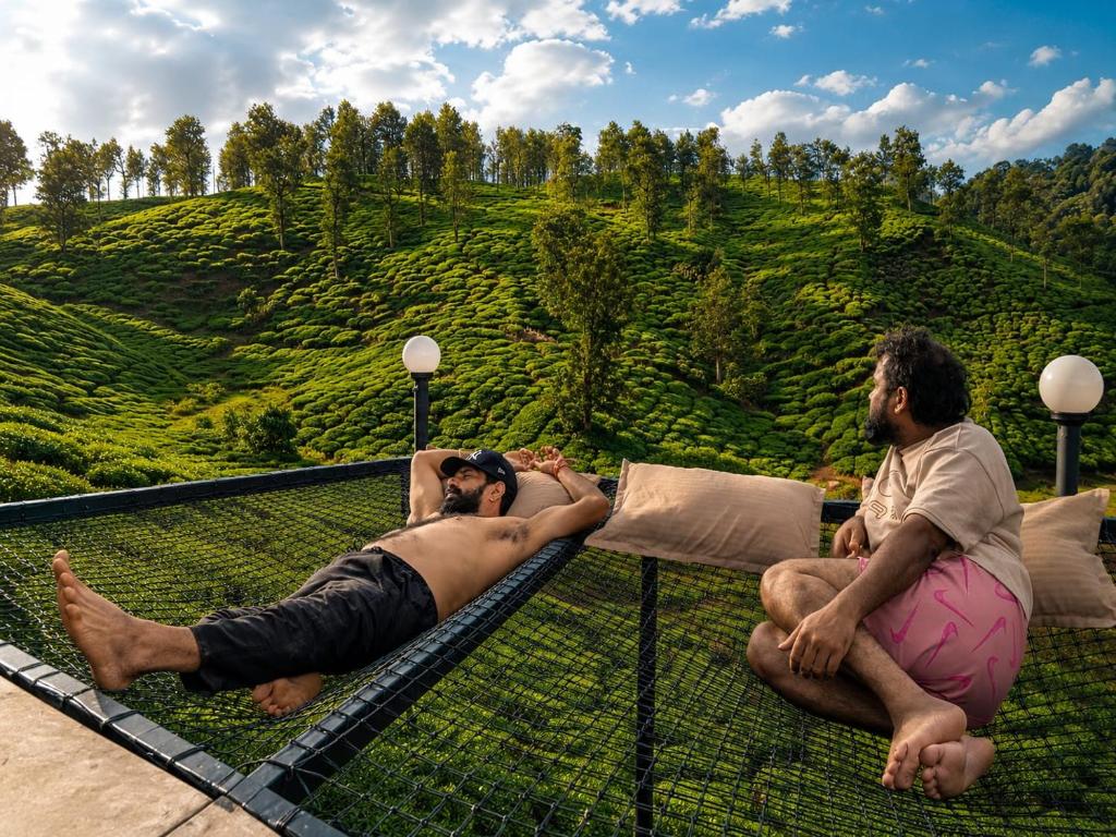 two men laying on top of a viewing platform overlooking a hill at Skydeck - Boche 1000 Acre in Meppādi